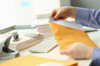 Businessperson opens yellow envelope with mail at workplace Businessperson opens yellow envelope with mail at workplace. Business correspondence and bank letter concept
