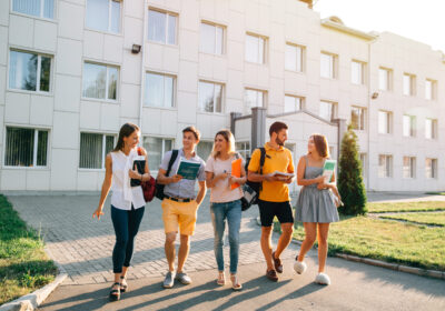 Five friendly students are walking after they passed test outside the college building and discuss the project Free time of a students, bachelor`s campus life rhythm. Five friendly students are walking after they passed test outside the college building and discuss the project, smiling, enjoying, carefree