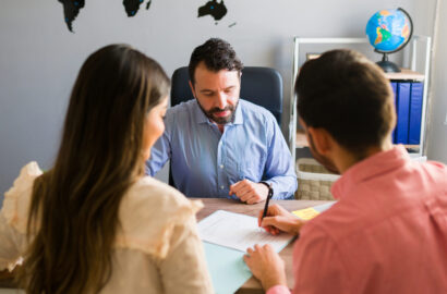 Tourists buying a trip abroad with a travel agent You got a deal. Young man signing a sales contract for a holiday vacation with his wife. Sales representative closing a deal for a timeshare sale with some customers at the travel agency